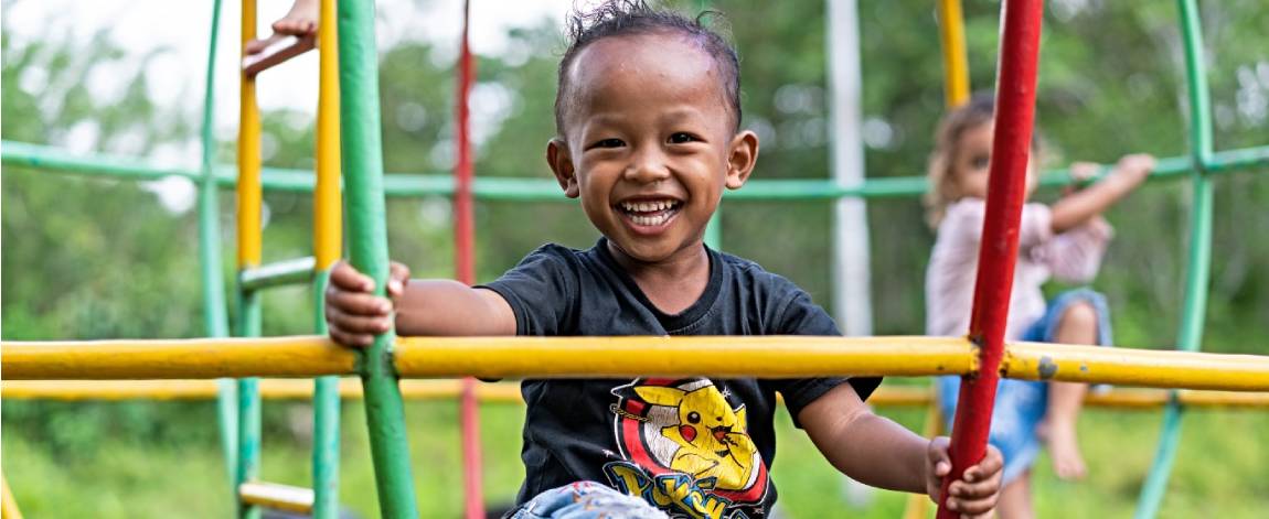 Young child smiling while playing with friends on playground